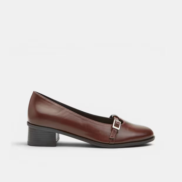 Brown leather block heel pump with square toe and side buckle strap detail.