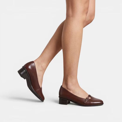 Brown leather block heel pumps on model, square toe with buckle strap.