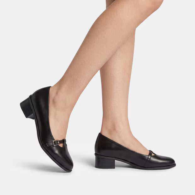 Black leather block-heel pump worn with adjustable buckle strap across vamp
